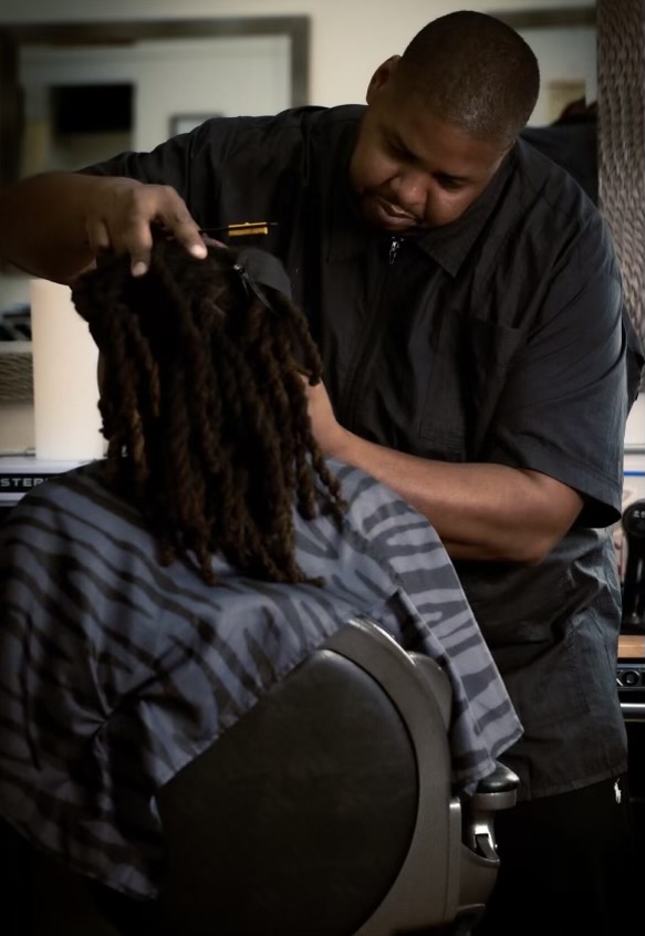 Barber giving a young child a haircut at D's Corner Unisex Salon in Detroit